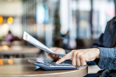 Accounting businessmen are pressing the calculator calculate the various costs that must be paid by the bill, Many invoices held and placed on the table, Financial and tax systems concept.の写真素材