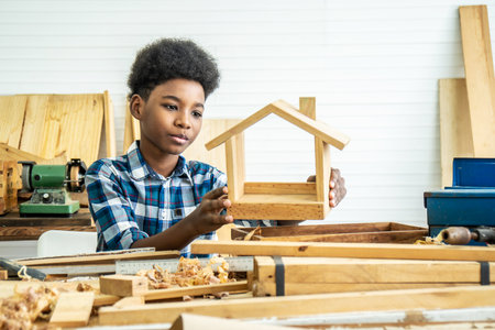 African-American boy carpenter looks at his own wooden house that helps his father happily do itの写真素材