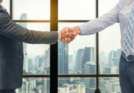 Close up of a business hand shake between two colleagues - greeting, dealing, merger and acquisition concepts on Modern glass building backgroundの写真素材