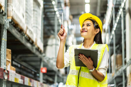 Portrait of smiling asian woman business using digital  tablet checking amount of stock product inventory on shelf at distribution warehouse factory, Logistics business planning conceptの写真素材