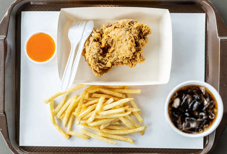 Top view of crispy fried chicken, french fries, chili sauce and soft drink on the side,  in the...
