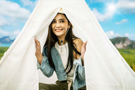 Asian beautiful woman is sitting inside the tent while camping outdoor during summer time in...