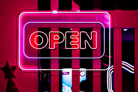 Neon light color blue Open sign on a glass window for business front of shop.の写真素材