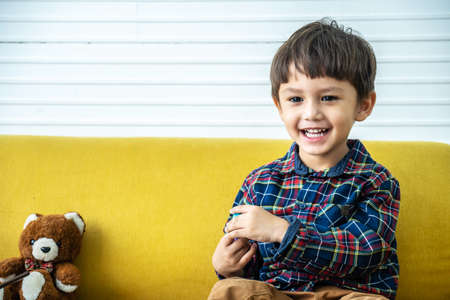 Handsome mixed race boy, playing in the living room in the house, playing with plasticine statue, happy child, little kid play with toys at home, He is wearing a long sleeve shirtの写真素材
