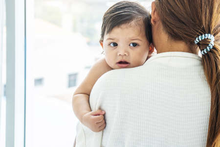 Loving mother holding and kisses the baby daughter,  A young mother  hugs and kisses her newborn...