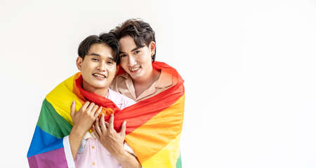 Guys spend time together at home, Portrait of Happy Asian gay couple embracing and showing their love under lgbt colorful rainbow flag. LGBT and love concept.の写真素材