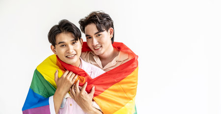 Guys spend time together at home, Portrait of Happy Asian gay couple embracing and showing their love under lgbt colorful rainbow flag. LGBT and love concept.の写真素材