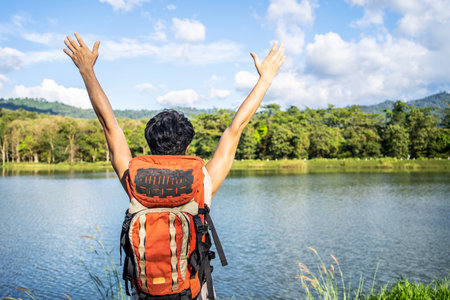 Young asian attractive tourists raise your fist above your head enjoying the nature, Male is happy to come to a picturesque place, spend time on vacation trip in thailandの写真素材
