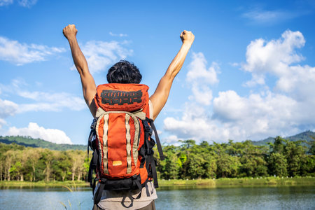 Young asian attractive tourists raise your fist above your head enjoying the nature, Male is happy to come to a picturesque place, spend time on vacation trip in thailandの写真素材