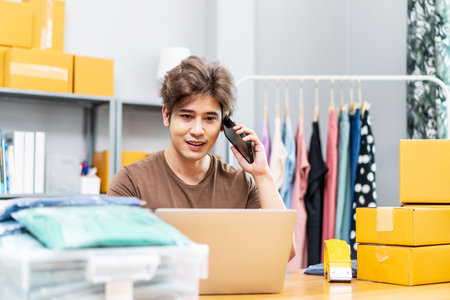 Startup small business entrepreneur SME, asian man receive order on phone. Portrait young Asian small business owner home office, packing boxes, SME sellers, e-commerce team, online salesの写真素材