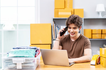 Startup small business entrepreneur SME, asian man receive order on phone. Portrait young Asian small business owner home office, packing boxes, SME sellers, e-commerce team, online salesの写真素材