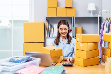 Starting Small business entrepreneur SME freelance, Young owner business woman received orders from clients and selling, calculate price of the products in parcel cardboard box packaging.の写真素材