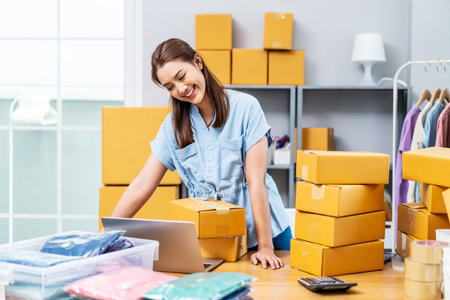 Portrait young attractive asia female owner startup business using computer laptops work happy with carton box at home prepare delivery to customers, procurement, omnichannel ecommerce online conceptの写真素材