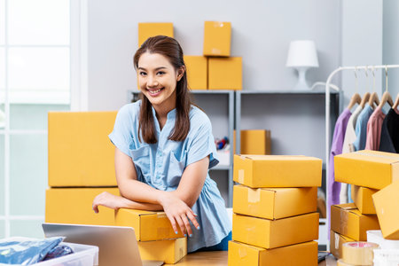 Portrait young attractive asia female owner startup business look at camera work happy with carton box at home prepare delivery to customers, procurement, omnichannel ecommerce online conceptの写真素材