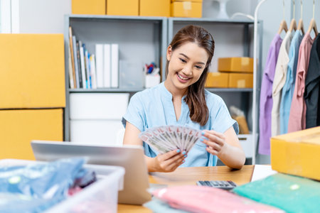 Entrepreneurs Small Business SME freelance, young Asian woman holding US dollars money lot of money happy and proud smile work at home, online marketing packing box delivery, online salesの写真素材