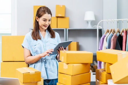 Young female owner startup received orders from clients and selling, Woman happy with box at home prepare parcel delivery in sme supply chain, procurement, omnichannel ecommerce online concept.の写真素材