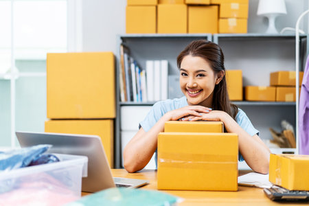 Portrait young attractive asia female owner startup business look at camera work happy with carton box at home prepare delivery to customers, procurement, omnichannel ecommerce online conceptの写真素材
