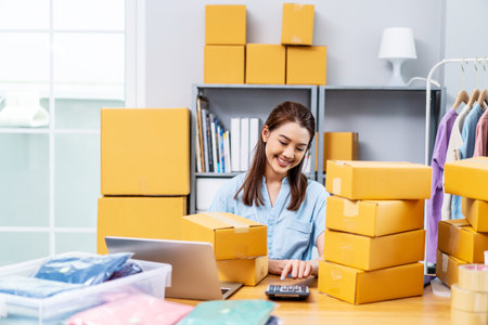 Starting Small business entrepreneur SME freelance, Young owner business woman received orders from clients and selling, calculate price of the products in parcel cardboard box packaging.の写真素材