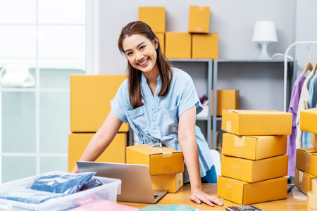 Portrait young attractive asia female owner startup business look at camera work happy with carton box at home prepare delivery to customers, procurement, omnichannel ecommerce online conceptの写真素材