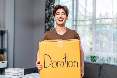 Donation Concept. Happy volunteer asian man holding a Donate Box for Giving, Smiling male working at charity center.の写真素材