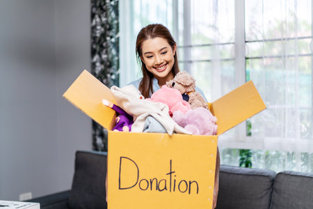 Donation Concept. Happy volunteer asian woman holding a Donate Box with full of toy doll, She working at charity center.の写真素材