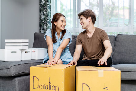Portrait of a happy young couple packing stuff clothes, object charity in cardboard box, reused for donate, Product recycle or volunteer sharing donation concept.の写真素材