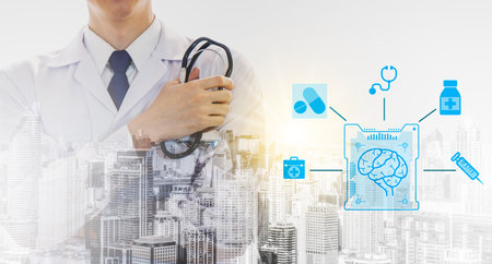 Front view of smart young male doctor crossed arm and holding stethoscope while standing outdoors with abstract city on background. Brain of a person and connection with medical equipment iconsの写真素材