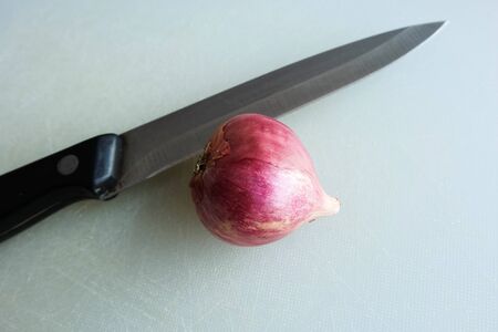 Knife and red onion on the cutting boardsの写真素材