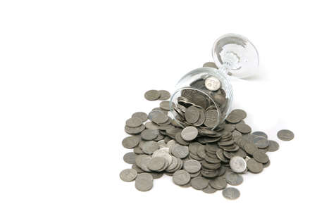 Wineglass with coins poured out over a white backgroundの写真素材