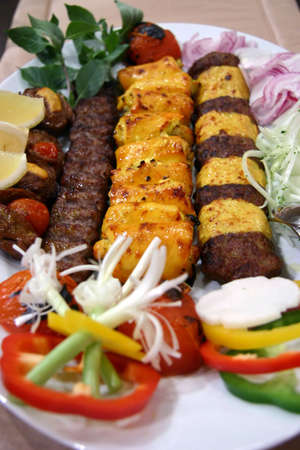 Long strips of lamb and chicken kebabs with relish, slice onions, turnip, capsicum, mint leaves and lemon wedgesの写真素材