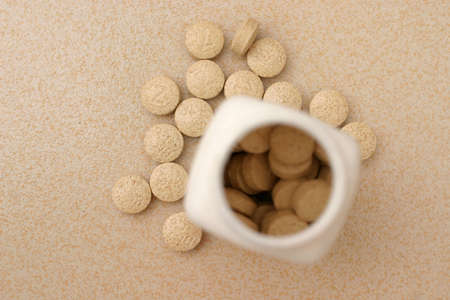 Bottle opening from top with scattered pills