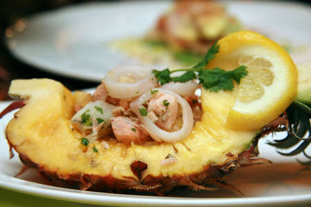 Cold cuttlefish salad on slice of carved open pineappleの写真素材