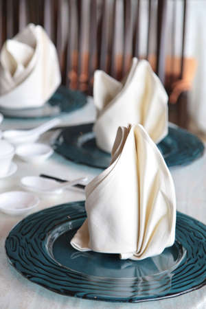 Fine dining Chinese cuisine table setting with glass plates and cotton fabric serviettesの写真素材
