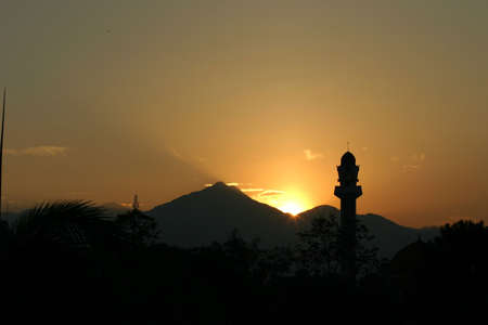 Silhouette of a mosque and hills at daybreak with sun just risingの写真素材