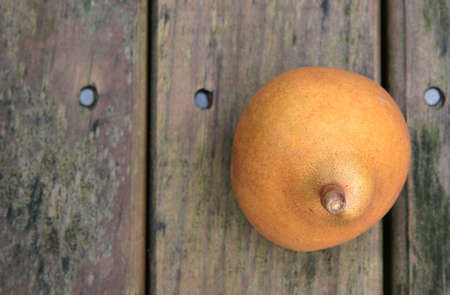 A yellow brown ripe pear on a weathered wooden park tableの写真素材
