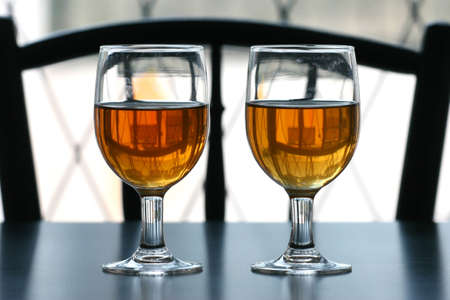 Two glasses of tea on a black table top with outdoor natural light behindの写真素材