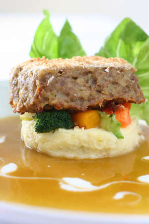 Gourmet meatloaf on a bed of vegetables and mash garnished with trimmed lettuceの写真素材