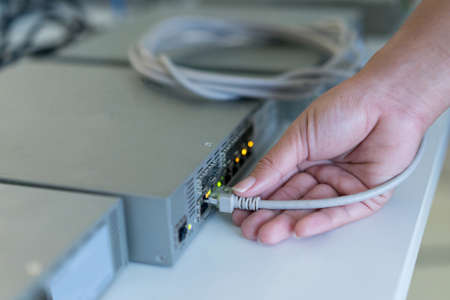 close up on engineering woman hand trying to connecting LAN to switch layer 2 for sharing file and...