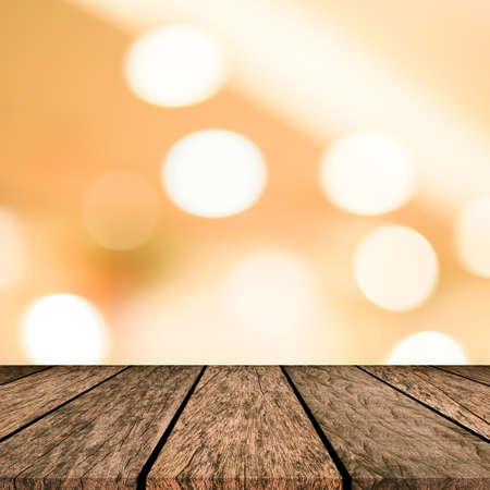 abstract blur beautiful gold color and circle bokeh light background with modern brown wood tabletop for show,ads,design product on display in the christmas festival and happy new year season conceptの写真素材