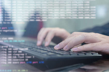 close up computer programmer man hand typing configuration on keyboard at laptop for input coding language to software for fix bug and defect of system in data center room , engineering and technologyの写真素材