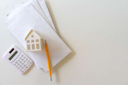 close up top view on house's model on mail letter with calculator and pencil on table for expense of...