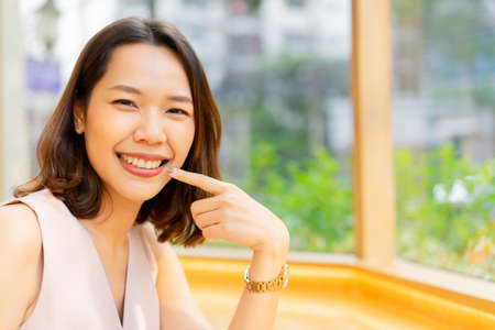 close up young beautiful asian woman smiling with happiness expression and using hand to pointing on...