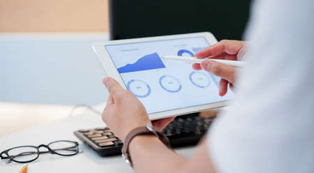 close up businessman hand using stylus pen on screen dashboard of graph and chart statistics data...