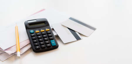 close up on calculator with group of mail letter and credit card at white table for end of the month expense day conceptの写真素材