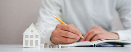 close up on house model with man working about check and summary expense of home loan mortgage for...