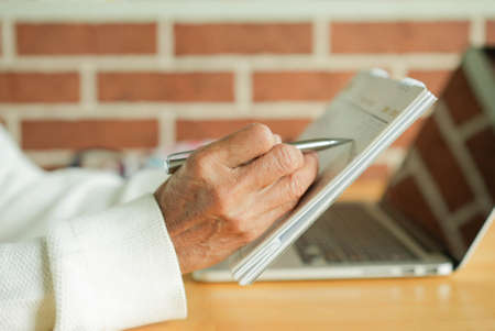 close up senior woman hand using en to mark or make appointment on calendar in home office for...