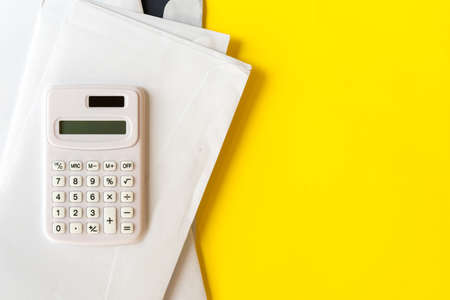 close up top of calculator with mail letters on yellow color background for utility expense of the month conceptの写真素材