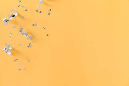 close up on group of silver color of rolling ribbon and confetti on yellow background with copy...