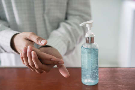 close up on sanitizer cleansing gel bottle with adult man washing and rubbing hand to protect virus and prevent coronavirus (MERS-n COV) and bacteria conceptの写真素材