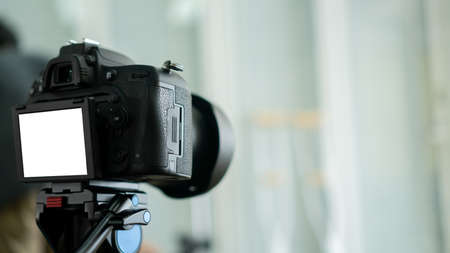 Close-up of a professional video camera with a white screen.